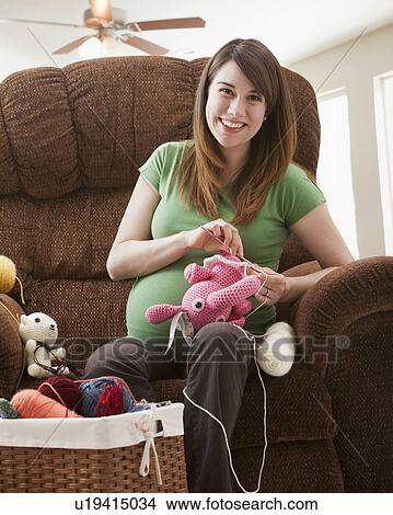 Picture - Portrait of pregnant woman preparing stuffed toys for baby. Fotosearch