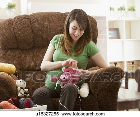 Stock Photography - Portrait of pregnant woman preparing stuffed toys for baby. Fotosearch