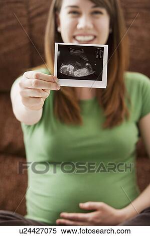 Stock Photography - Portrait of pregnant woman showing ultrasonography scan. Fotosearch