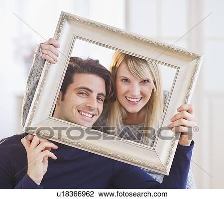 Portrait of smiling couple holding picture frame View Large Photo Image Stock Image - Portrait of smiling couple holding picture frame. Fotosearch
