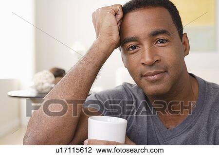 Stock Image - Portrait of smiling mature man holding mug. Fotosearch