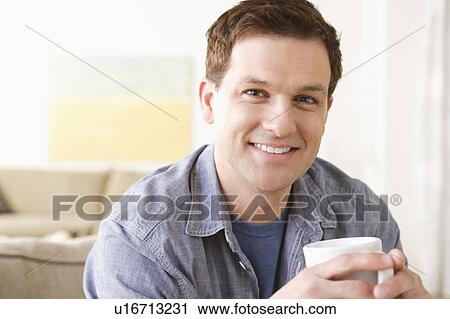 Stock Image - Portrait of smiling mid adult man holding mug. Fotosearch