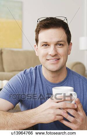 Stock Photograph - Portrait of smiling mid adult man holding mug. Fotosearch