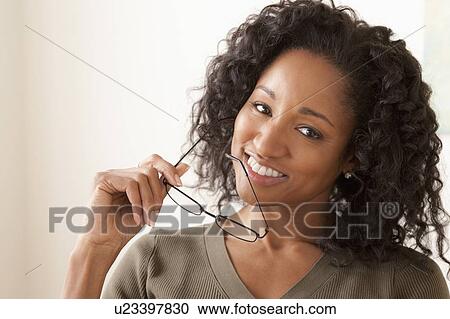 Stock Image - Portrait of smiling mid adult woman holding glasses. Fotosearch