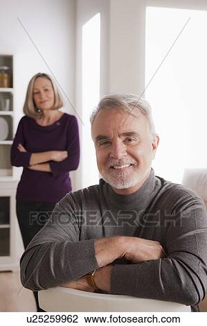 Stock Image - Portrait of smiling senior man, senior woman in background. Fotosearch