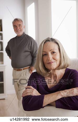 Stock Image - Portrait of smiling senior woman, senior man in background. Fotosearch