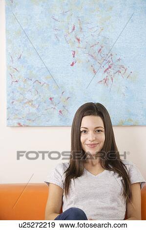 Portrait of smiling woman sitting on sofa View Large Photo Image Stock Photo - Portrait of smiling woman sitting on sofa. Fotosearch