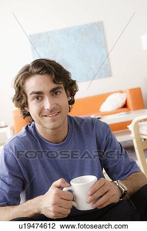 Portrait of smiling young man holding mug View Large Photo Image Stock Image - Portrait of smiling young man holding mug. Fotosearch