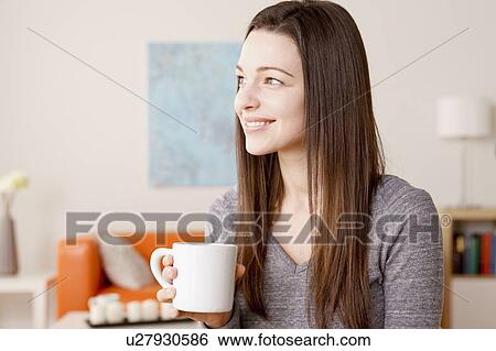 Stock Photograph - Portrait of smiling young woman holding mug. Fotosearch