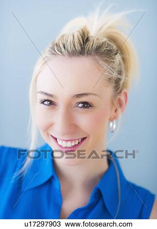 Stock Image - Portrait of smiling young woman, studio shot. Fotosearch