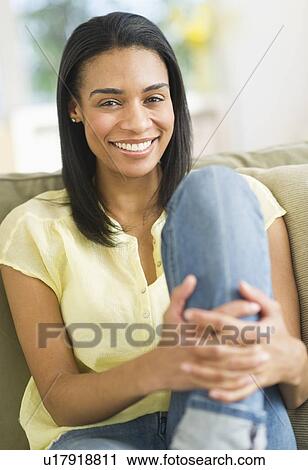 Stock Image - Portrait of woman sitting on sofa. Fotosearch