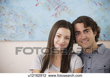 Portrait of young couple sitting on sofa View Large Photo Image Stock Image - Portrait of young couple sitting on sofa. Fotosearch