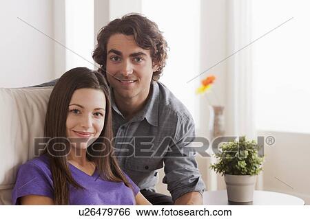 Portrait of young couple sitting on sofa View Large Photo Image Stock Photograph - Portrait of young couple sitting on sofa. Fotosearch