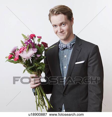 Stock Photo - Portrait of young handsome man holding bunch of flowers. Fotosearch