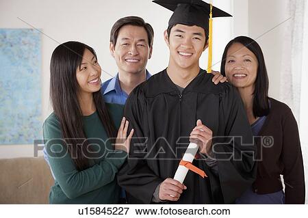 Stock Photo - Portrait of young man in graduation gown with family. Fotosearch