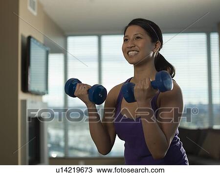 Portrait of Young woman exercising at home with dumbbells View Large Photo Image Stock Image - Portrait of Young woman exercising at home with dumbbells. Fotosearch