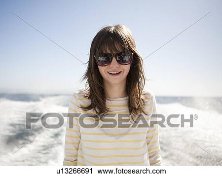 Stock Image - Portrait of young woman in sunglasses in front of sea. Fotosearch