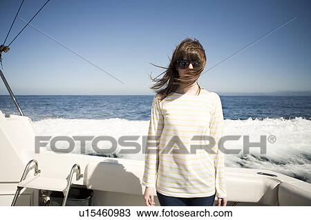 Stock Image - Portrait of young woman in sunglasses in front of sea. Fotosearch