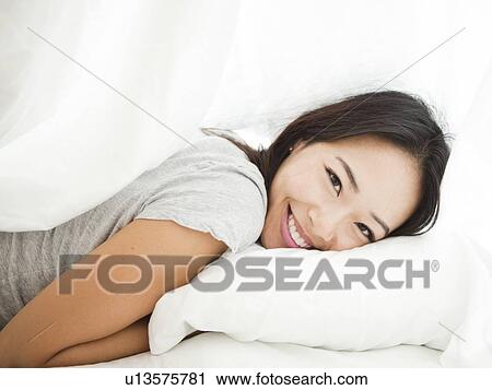 Stock Image - Portrait of young woman lying down. Fotosearch