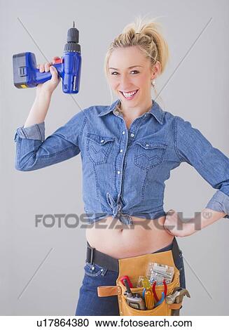 Portrait of young woman wearing tool belt and holding drill, studio shot View Large Photo Image Stock Image - Portrait of young woman wearing tool belt and holding drill, studio shot. Fotosearch