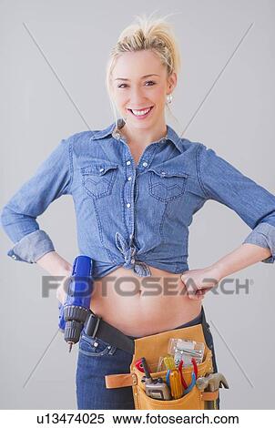 Portrait of young woman wearing tool belt and holding drill, studio shot View Large Photo Image Stock Photography - Portrait of young woman wearing tool belt and holding drill, studio shot. Fotosearch