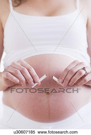 Stock Photography - Pregnant woman holding broken cigarette. Fotosearch