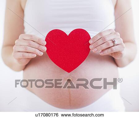 Pregnant woman holding red paper heart on her belly View Large Photo Image Stock Photograph - Pregnant woman holding red paper heart on her belly. Fotosearch
