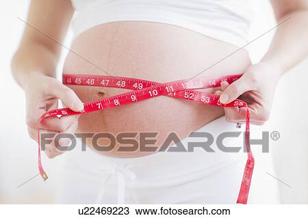 Pregnant woman measuring her belly View Large Photo Image Stock Image - Pregnant woman measuring her belly. Fotosearch