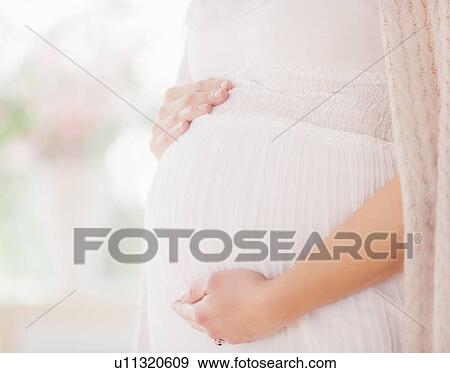 Stock Photo - Pregnant woman touching her belly. Fotosearch