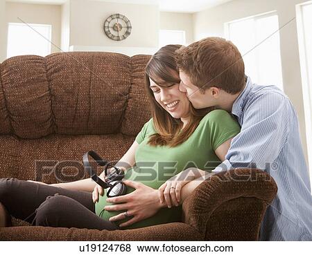 Pregnant woman with boyfriend holding headphones on belly View Large Photo Image Stock Photo - Pregnant woman with boyfriend holding headphones on belly. Fotosearch