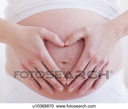 Pregnant woman with hands folded as heart on her belly View Large Photo Image Stock Image - Pregnant woman with hands folded as heart on her belly. Fotosearch