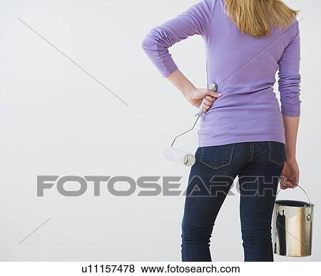 Rear view of woman holding paint can and paint roller View Large Photo Image Stock Photo - Rear view of woman holding paint can and paint roller. Fotosearch