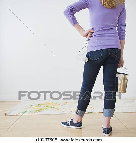 Stock Photography - Rear view of woman holding paint can and paint roller. Fotosearch