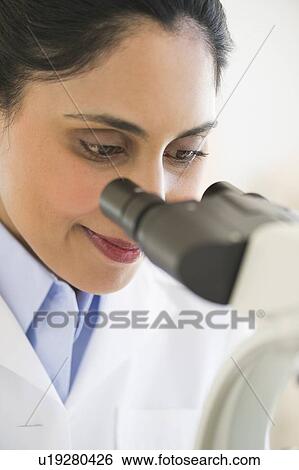Stock Photograph - Scientist looking through microscope. Fotosearch