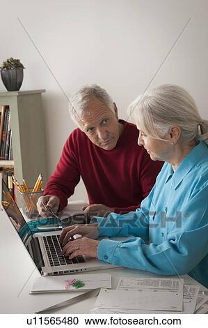 Senior couple working together in home office View Large Photo Image Stock Image - Senior couple working together in home office. Fotosearch