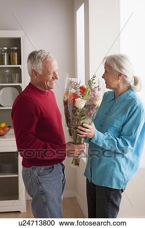 Senior man giving flower to woman View Large Photo Image Stock Image - Senior man giving flower to woman. Fotosearch