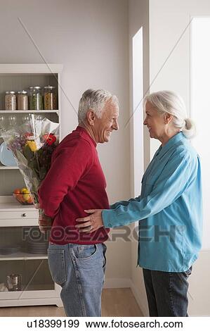 Stock Photo - Senior man giving flower to woman. Fotosearch