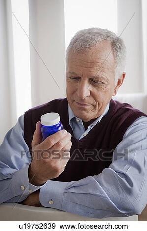 Senior man reading label on medicine bottle View Large Photo Image Stock Photo - Senior man reading label on medicine bottle. Fotosearch