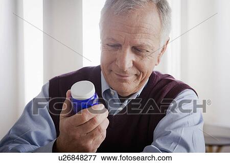Senior man reading label on medicine bottle View Large Photo Image Stock Photo - Senior man reading label on medicine bottle. Fotosearch