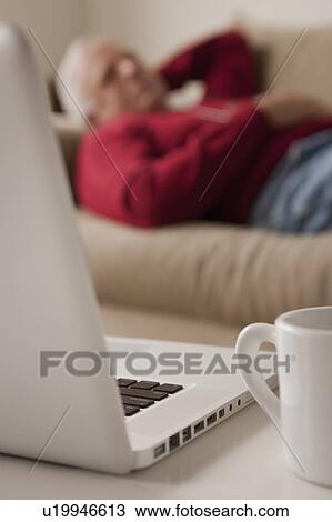 Senior man sleeping on sofa, laptop and mug in foreground View Large Photo Image Stock Image - Senior man sleeping on sofa, laptop and mug in foreground. Fotosearch