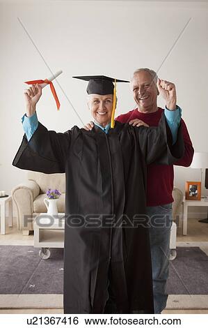 Senior woman wearing graduation gown, happy man in background View Large Photo Image Stock Photograph - Senior woman wearing graduation gown, happy man in background. Fotosearch