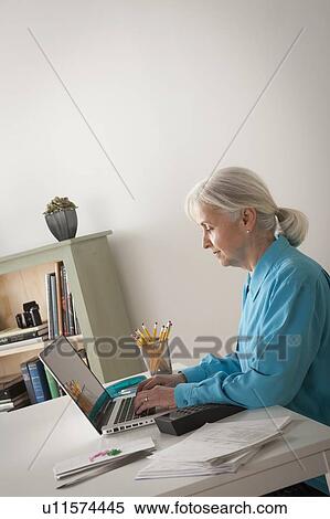 Senior woman working on laptop in home office View Large Photo Image Stock Photography - Senior woman working on laptop in home office. Fotosearch
