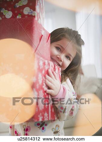 Stock Image - Small girl (4-5 years) carrying Christmas presents. Fotosearch