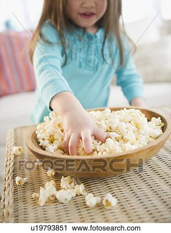 Stock Image - Small girl (4-5 years) eating popcorn. Fotosearch
