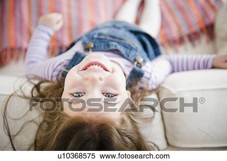 Stock Photography - Small girl (4-5 years) lying on sofa. Fotosearch