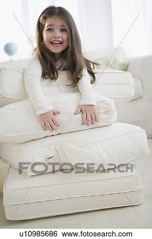 Stock Photograph - Small girl (4-5 years) playing with cushions. Fotosearch