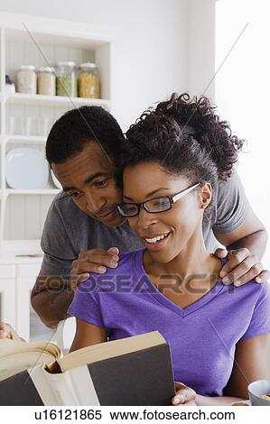 Stock Photography - Smiling couple reading book together. Fotosearch
