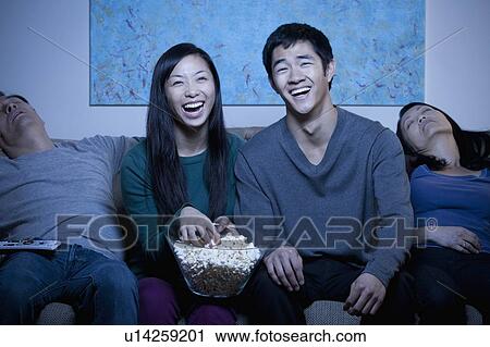 Smiling family watching TV and eating popcorn View Large Photo Image Stock Image - Smiling family watching TV and eating popcorn. Fotosearch