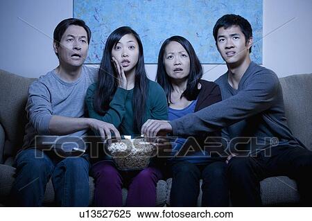 Smiling family watching TV and eating popcorn View Large Photo Image Stock Photography - Smiling family watching TV and eating popcorn. Fotosearch