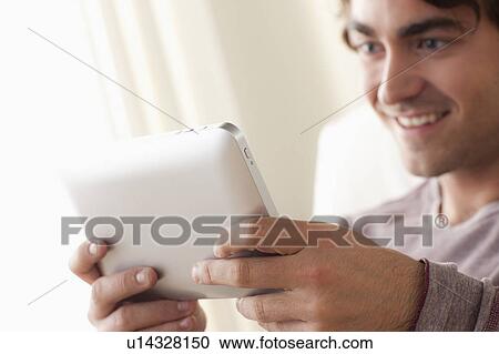 Stock Image - Smiling man using digital tablet. Fotosearch